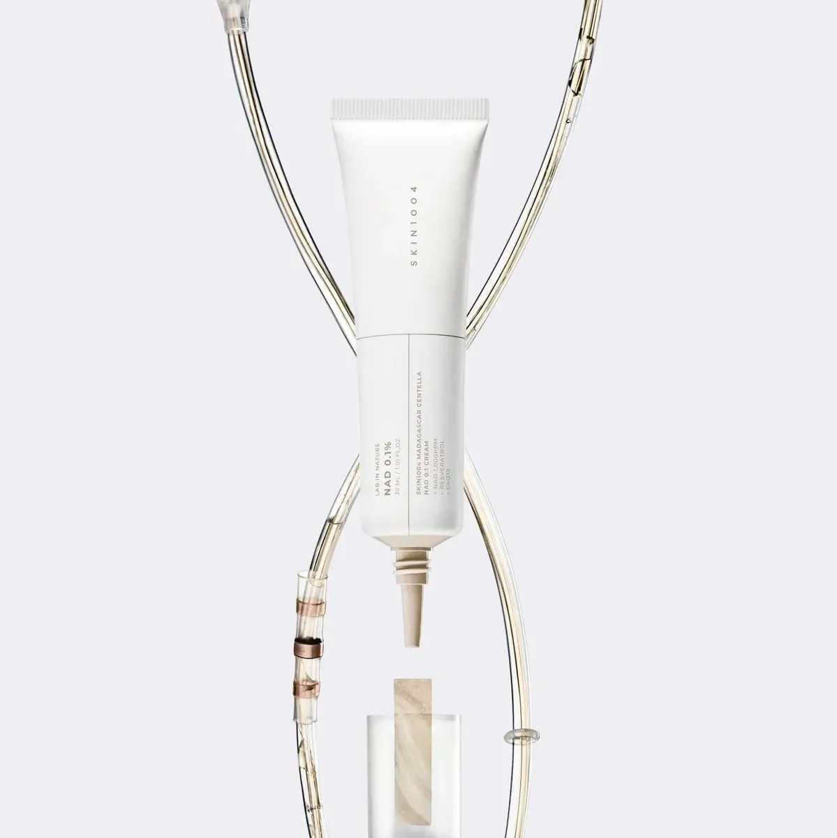 SKIN1004 Madagascar Centella NAD 0.1 Cream — туба на сірому тлі з тонкими золотими ланцюжками