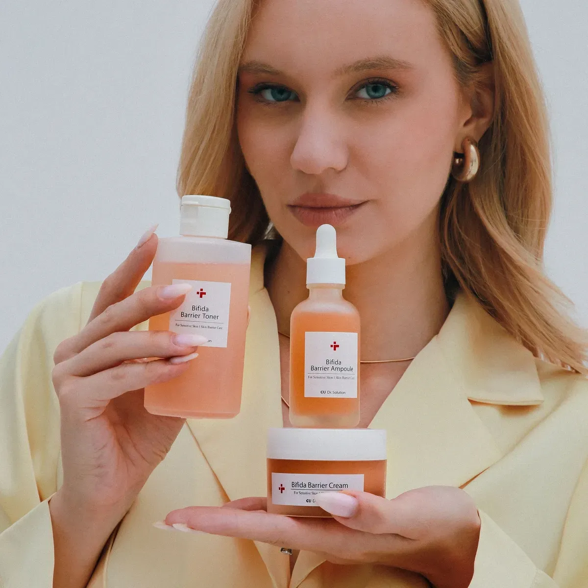 CU SKIN Bifida Barrier — тонер, ампула і крем лінійки в руках моделі